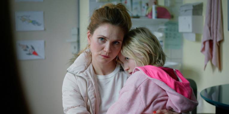 Zu sehen ist eine person die ein kleines kind in ihren armen hält.